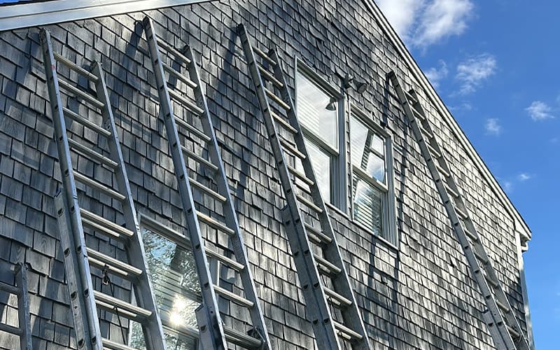 Exterior siding painting with ladders